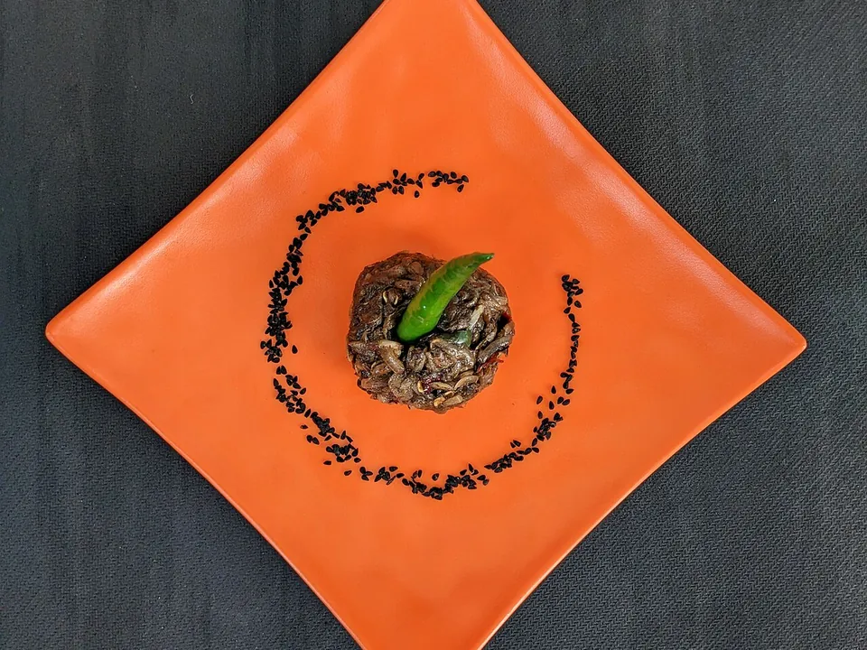 Chepa shutki vorta — dark, spicy fermented fish vorta served on an orange plate