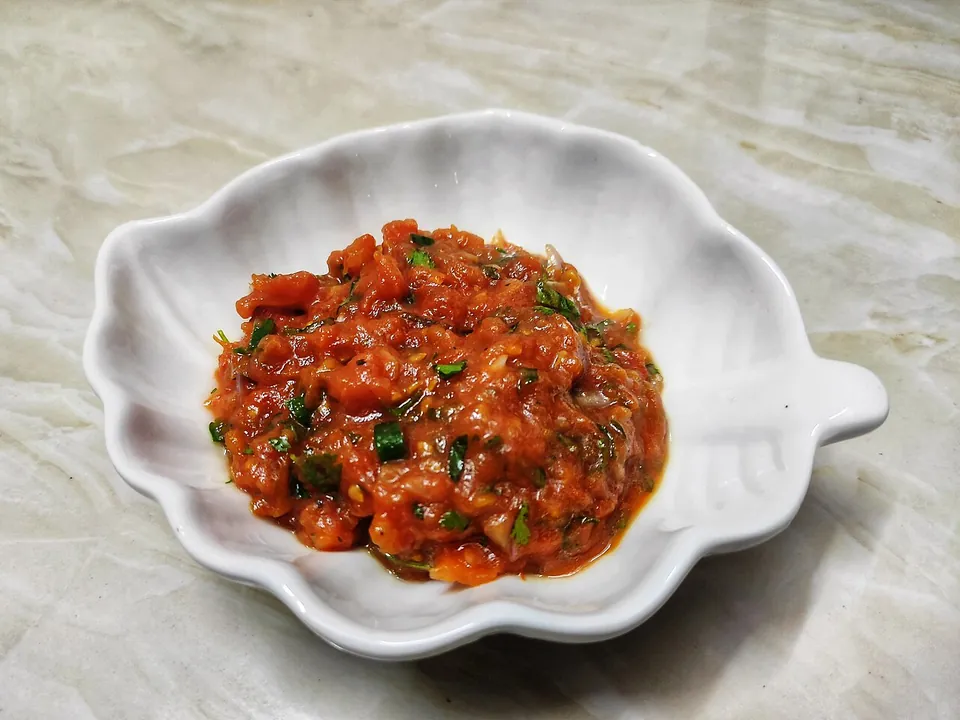 Tomato vorta — roasted tomato mash with green chili and cilantro in a white leaf-shaped dish
